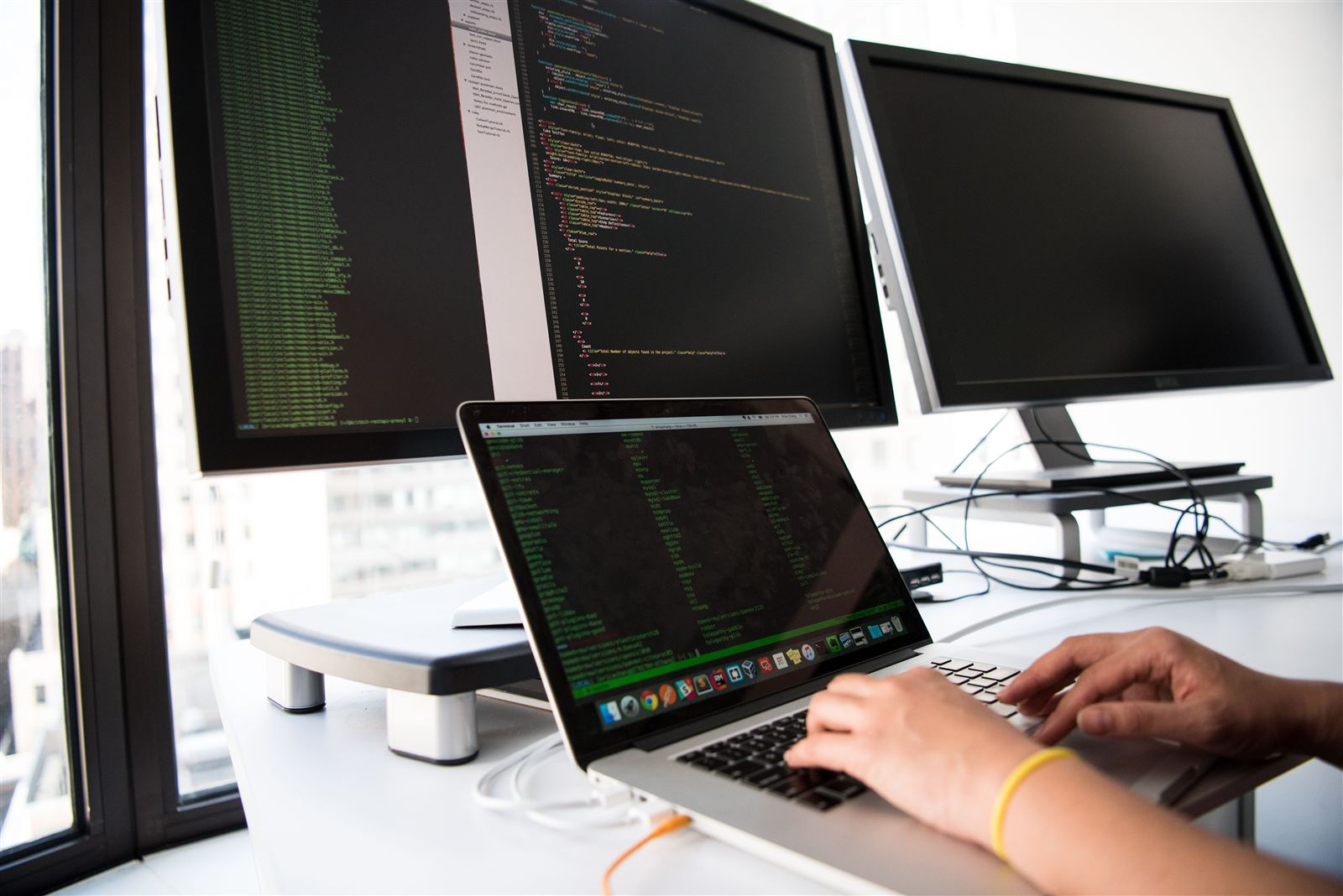 Developer building a custom web application on a laptop and multiple monitors